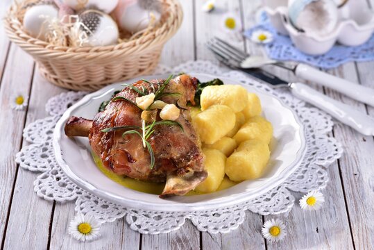 Leg of lamb with spinach and potato dumplings in spring with daisy flowers in the background