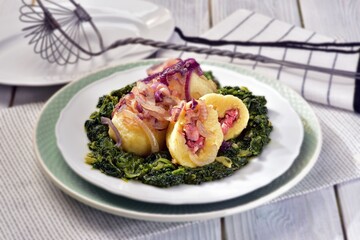 Potato dumplings filled with smoked meat served with spinach