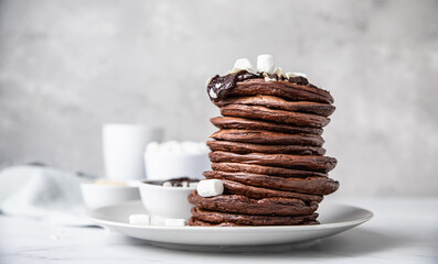 Chocolate pancakes with melted chocolate, ground almond and marshmallow, light background.