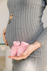 girl's pregnant belly with a little shoe in her hand over her belly