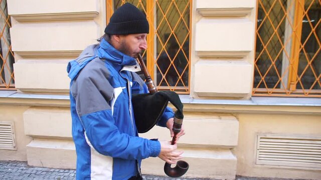 A man walks down the street and plays a musical instrument. A game in motion. Attracting the attention of passers-by. Demonstration of skills.