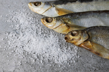 Dried salted fish and sprinkled sea salt on a concrete background. Homemade food, beer snack. High quality photo