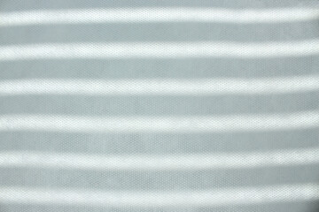 Fototapeta premium The blinds cast a shadow over the white fabric. Sunny day. Concept of white and black stripes of life, textile