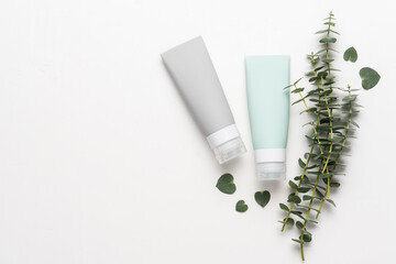 Cosmetics bottles containers on white background with eucalyptus branches. Mockup of pastel green bottle plastic tube for branding of medicine or cosmetics - cream, gel, skin care, toothpaste