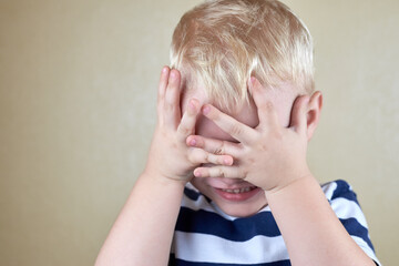 Little lonely boy covered his face with his hands.