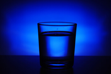 A glass with water at blue background