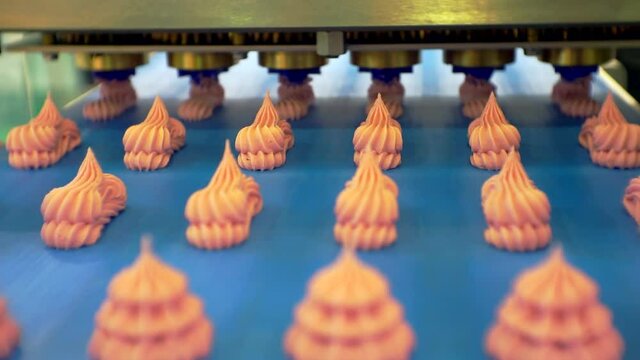 modern food production. a special machine makes cakes from thick cream. the finished cakes move slowly along the conveyor belt. filming a close-up of a technological process. shallow depth of field