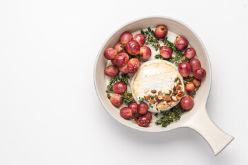 Baked camembert cheese with grapes, nuts, honey and thyme. White food background