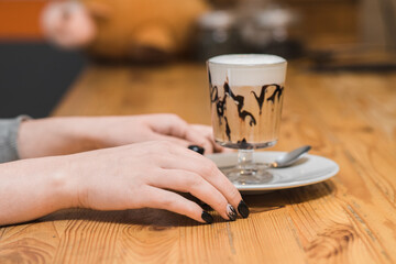 Photo of female hands of a visitor to a coffee shop with a delicious coffee punch