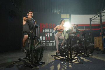 Group of multi ethnic people riding spinning bike or bicycle, Muscle strength training workout at gym fitness center club. Exercise with sport equipment. People lifestyle recreation. Strong team