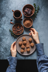 Natural vegan candy truffles made from dates, nuts and cocoa. Ingredients for cooking bowls on dark gray background