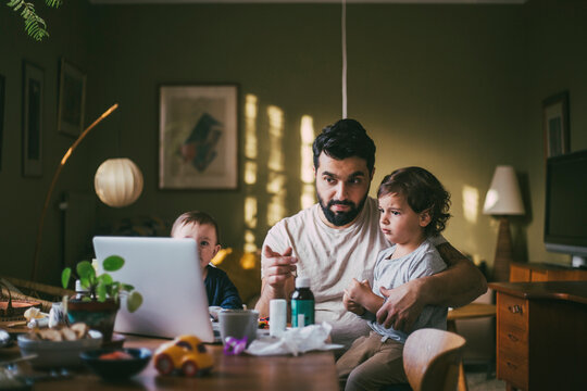 Father with children taking advice on video call through laptop at home during pandemic