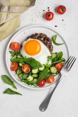 Chopped beef steak with fried egg and salad. Delicacy dinner in  plate on white background. Healthy food concept