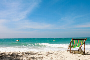 Green Deck chair at the tropical sandy beach with blue wave and clear sky in summer time