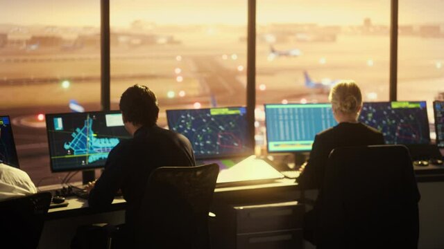 Diverse Air Traffic Control Team Working in a Modern Airport Tower at Sunset. Office Room is Full of Desktop Computer Displays with Navigation Screens, Airplane Flight Radar Data for Controllers.