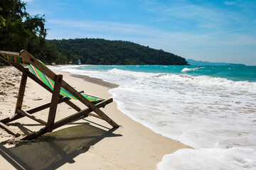 Green Deck chair at the tropical sandy beach with blue wave and clear sky in summer time