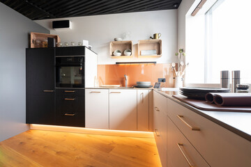 modern kitchen with led illuminated plinth, wooden floor and black ceiling