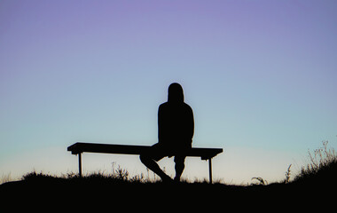 silhouette of a person sitting on a bench