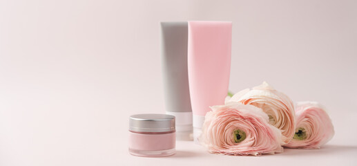 Cosmetics beauty cream with delicate flowers. Natural cosmetics for face and body. Close-up and side view on pink background
