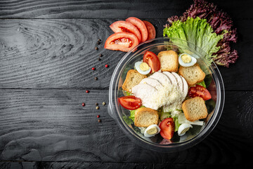 Healthy salad caesar in plastic package on black background. for take away or food delivery. banner, menu recipe place for text, top view