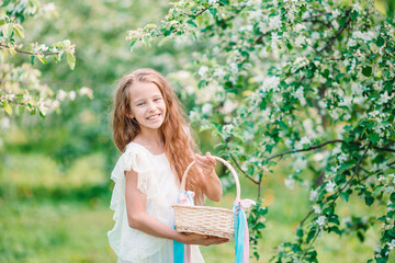 Adorable little girl in blooming apple garden on beautiful spring day