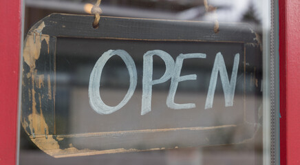 sign with the word open on a glass door of a shop