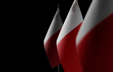 Small national flags of the Malta on a black background