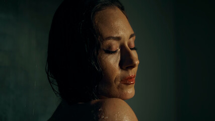 Young European girl long-haired brunette stands in a dark shower