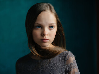 Cute little girl of models on a green background in a gray dress and hairstyle