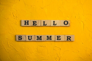 Top view Hello summer lettering of alphabet wooden blocks  on  yellow background