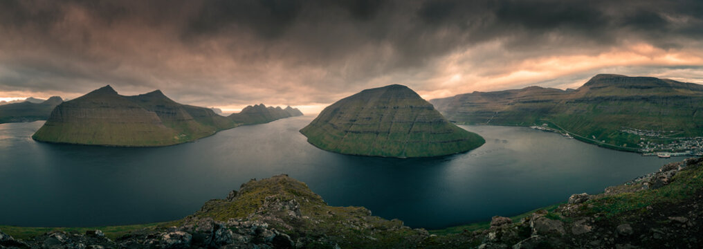 Panoramic landscape scenery at the Klakkur viewpoint near Klaksvik on the island of Bordoy with a view of Kalsoy and Kunoy in sunset, dramatic cloudy sky, fjords and mountains, Faroe Islands.