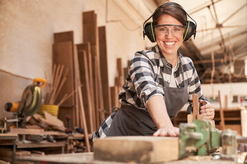 Woman as a carpenter trainee at the planer - obrazy, fototapety, plakaty