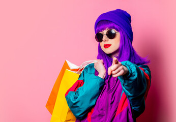 Stylish shopaholic girl in 80s tracksuit and sunglasses hold shopping bags - obrazy, fototapety, plakaty