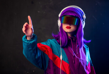 Stylish girl in cyber punk glasses and 80s tracksuit with headphones on dark background