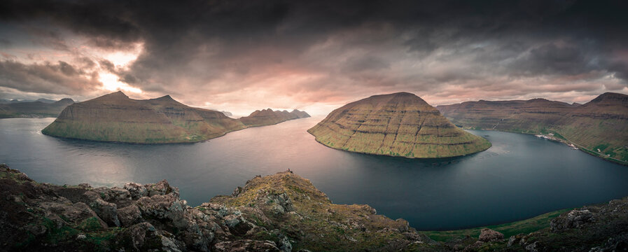 Panoramic landscape scenery at the Klakkur viewpoint near Klaksvik on the island of Bordoy with a view of Kalsoy and Kunoy in sunset, dramatic cloudy sky, fjords and mountains, Faroe Islands.