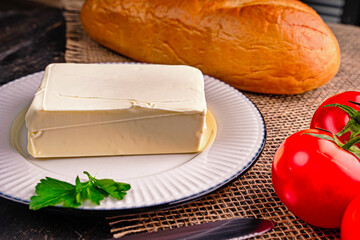 Fresh tasty butter on a kitchen table. A piece of butter on a white plate. 