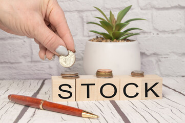 Hand putting coins on stack stair as step growing growth and wooden cube block with word STOCKS. Investment and save money concept