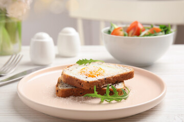 Delicious breakfast with fried egg, toasted bread and arugula served on white wooden table