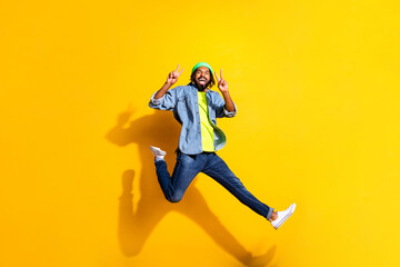 Fototapeta na wymiar Full size photo of young happy excited positive afro man jumping showing v-sign isolated on yellow color background