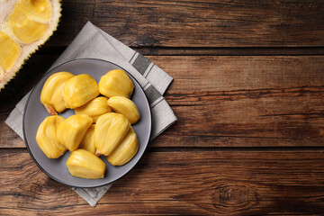 Delicious exotic jackfruit bulbs on wooden table, flat lay. Space for text