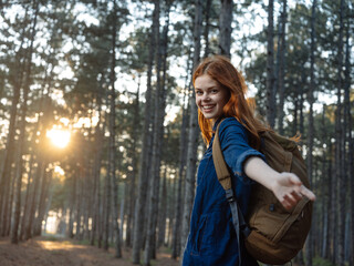 Traveler with a backpack at sunset in a pine forest