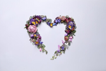 Beautiful heart shaped floral composition on light background, flat lay