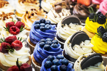 Close up of freshly baked cakes and cupcakes with berries and other fillings