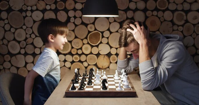 Father and his little son playing chess at home