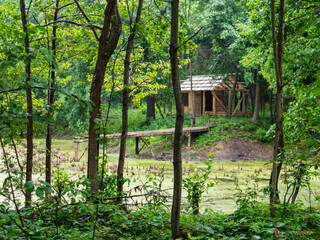 unfinished hut on the shore of a pond with a pier