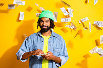 Photo of young happy cheerful smiling positive cool man with lot of money isolated on yellow color background