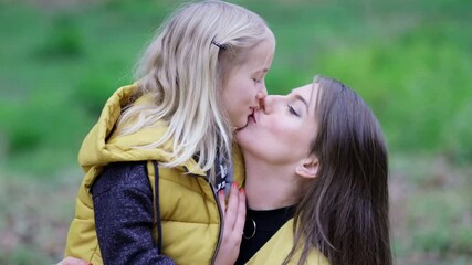 Kissing and hugging happy family. Beautiful Mother And her little daughter outdoors. Nature. Beauty Mum and her Child playing in Park together. video stock footage. Slow motion soft focus - Powered by Adobe