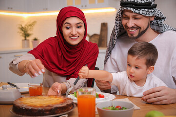 Happy Muslim family eating together at table in kitchen