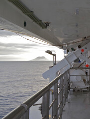 Modern white cruiseship or cruise ship liner at sea cruising the Mediterranean with Liparic Islands...