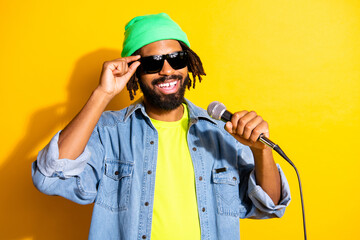 Photo of young handsome positive good mood cheerful afro man singing in karaoke isolated on yellow color background